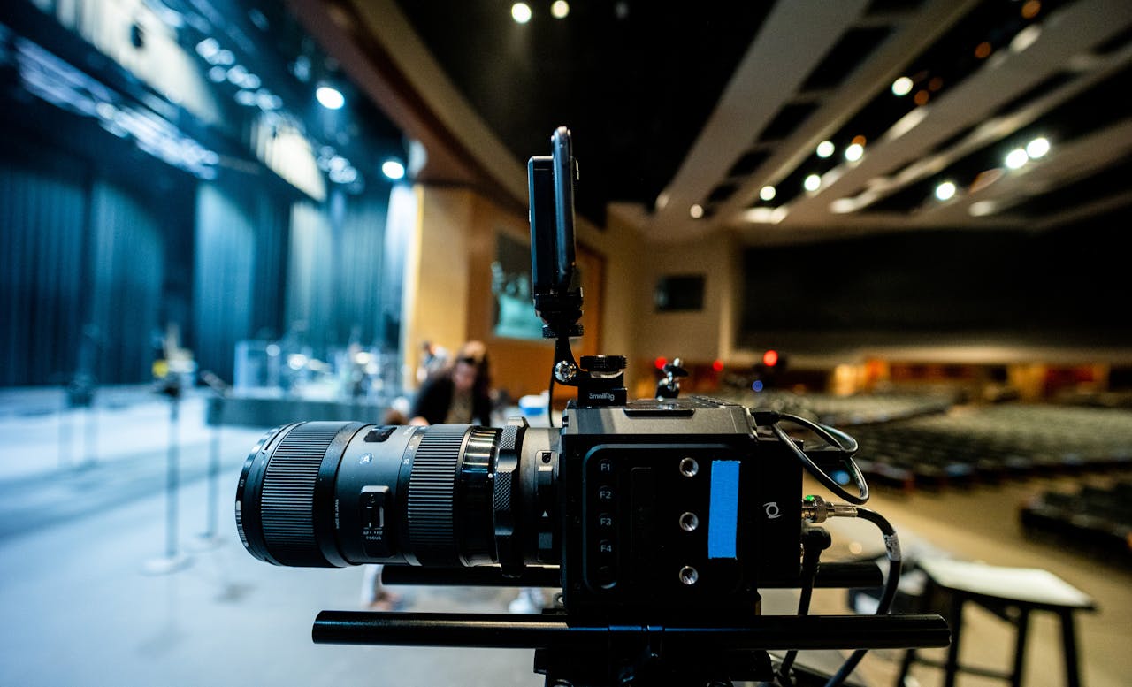 Close-up of a professional video camera in a modern auditorium setting.